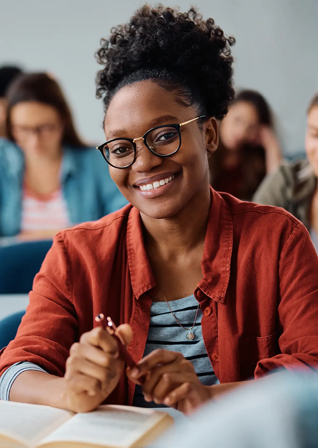 Student smiling at the camera with others in the background